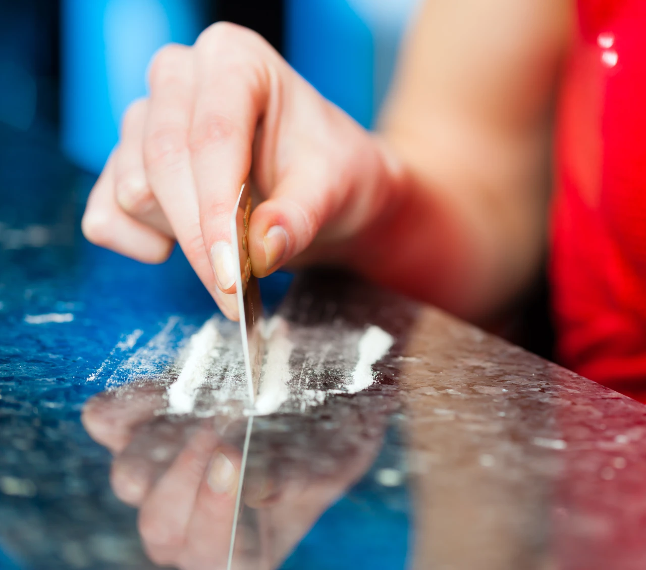 Vrouw legt lijntjes coke op tafel met bankpas omdat ze een cocaineverslaving heeft.