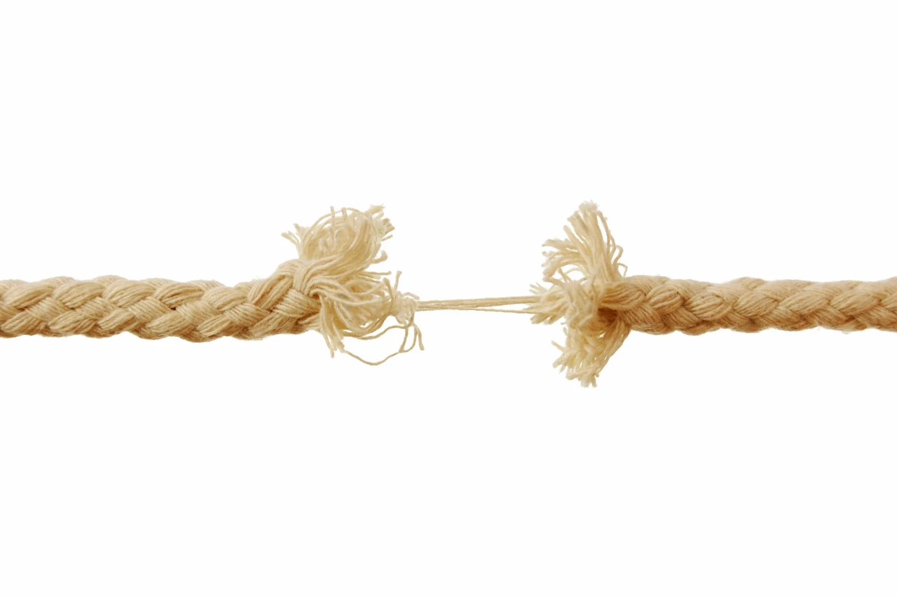Geel touw dat in het midden met nog maar paar draden aan elkaar vastzit.