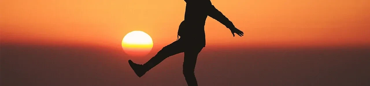 Persoon zonder hoofd balanceert op 1 been bij zonsopgang of zonsondergang.